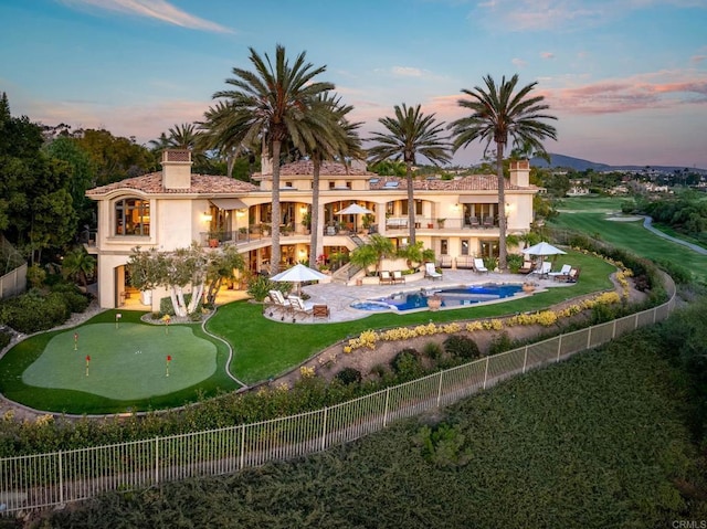 7756 St Andrews Rd, Rancho Santa Fe, CA 92067 - back of house at dusk featuring a patio, a balcony, a fenced backyard, and a chimney