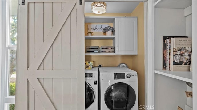 laundry area featuring cabinet space, a barn door, and washing machine and clothes dryer