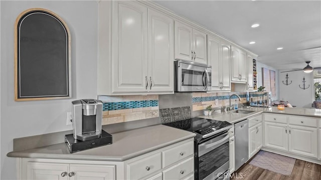kitchen with a sink, stainless steel appliances, a ceiling fan, white cabinetry, and backsplash