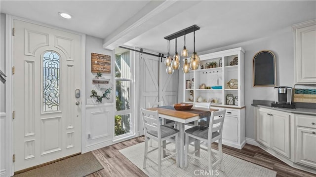 dining area featuring dark wood-style flooring, a notable chandelier, a barn door, and recessed lighting
