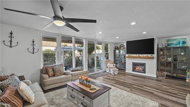 living room featuring expansive windows, ceiling fan, and light hardwood / wood-style flooring