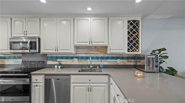 kitchen featuring white cabinetry, sink, backsplash, and appliances with stainless steel finishes