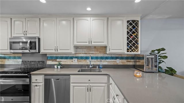 kitchen featuring white cabinets, appliances with stainless steel finishes, a sink, light countertops, and backsplash