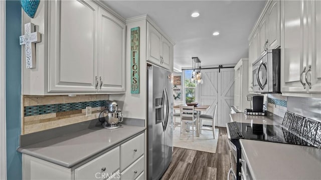 kitchen featuring a barn door, tasteful backsplash, white cabinets, and stainless steel appliances