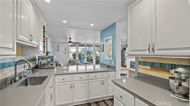 kitchen with a sink, white cabinetry, ceiling fan, and tasteful backsplash