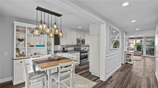 kitchen featuring backsplash, pendant lighting, appliances with stainless steel finishes, dark wood finished floors, and white cabinets