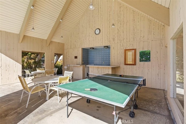 recreation room with wooden walls, high vaulted ceiling, and beamed ceiling