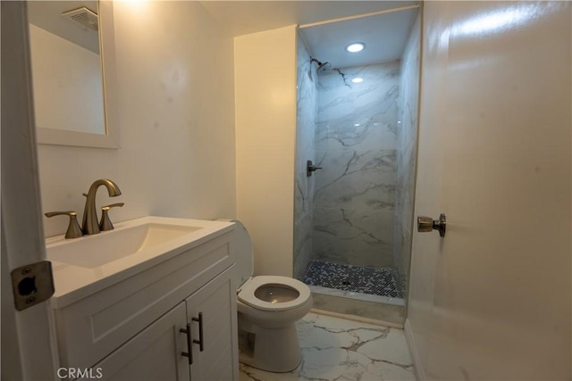 bathroom featuring vanity, tiled shower, and toilet