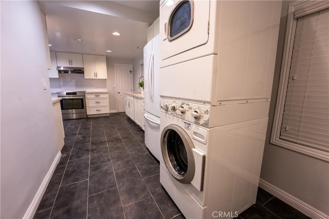 clothes washing area featuring stacked washer / dryer and dark tile patterned flooring