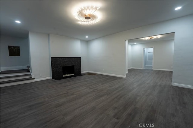 unfurnished living room featuring baseboards, dark wood finished floors, recessed lighting, a fireplace, and stairs