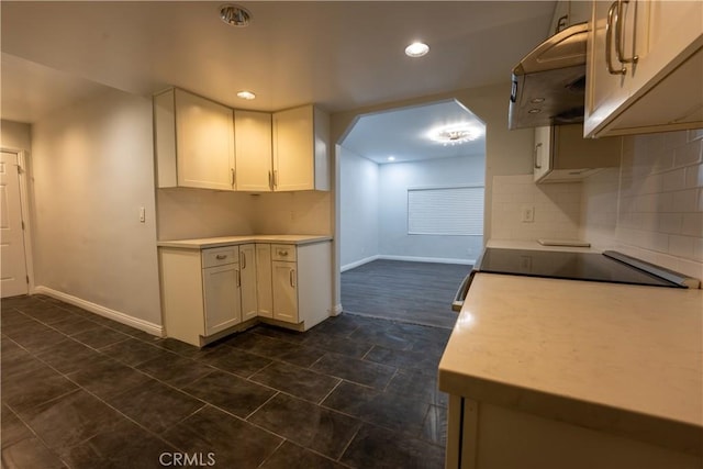 kitchen with white cabinetry, backsplash, range hood, and dark tile patterned flooring