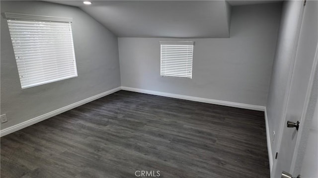 bonus room with a wealth of natural light, vaulted ceiling, dark wood finished floors, and baseboards