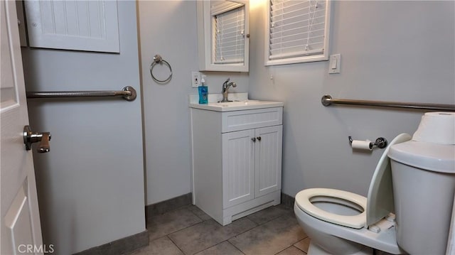 half bathroom featuring tile patterned flooring, baseboards, vanity, and toilet