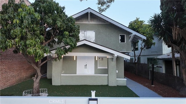 view of front facade with fence and stucco siding