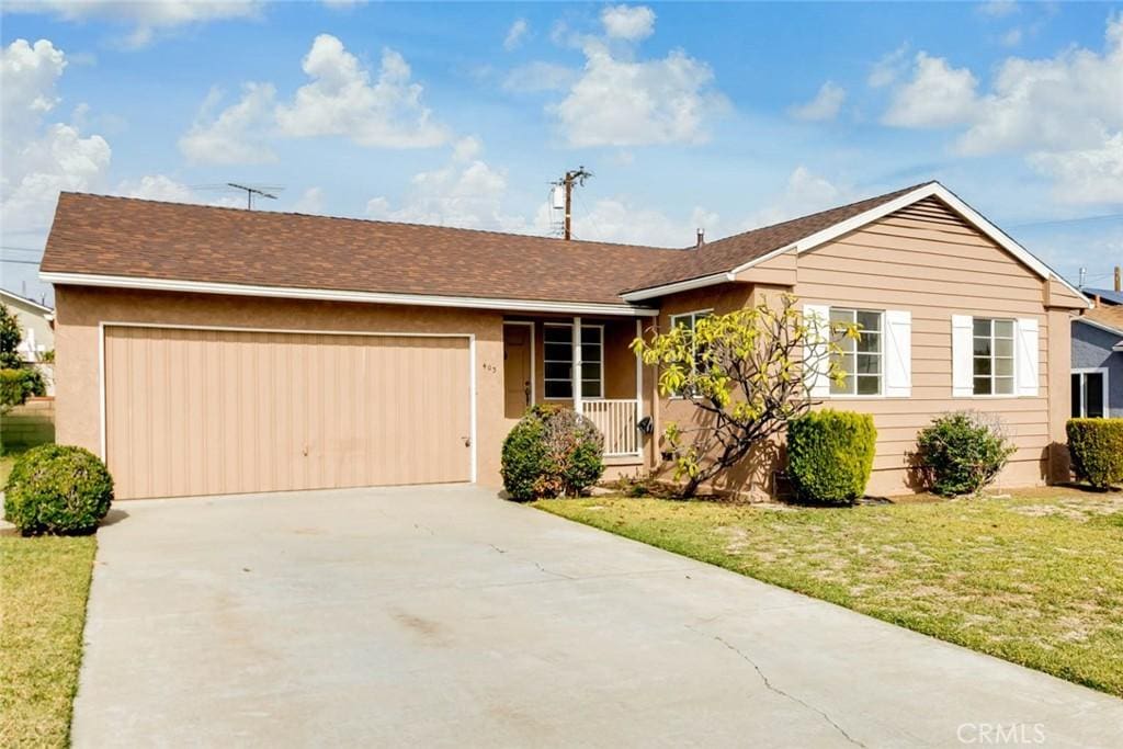 ranch-style home with a garage, covered porch, and a front lawn