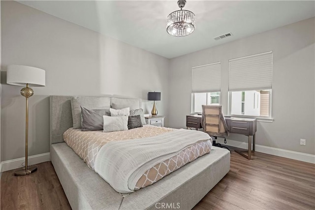 bedroom with hardwood / wood-style floors and a notable chandelier