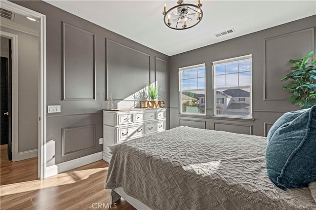 bedroom with an inviting chandelier and light wood-type flooring