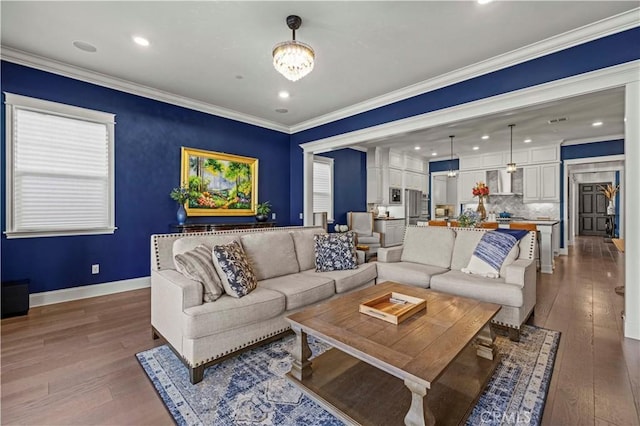 living room featuring dark wood-type flooring, ornamental molding, and a notable chandelier