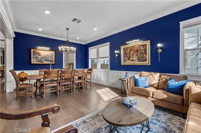 living room with a notable chandelier, crown molding, a wealth of natural light, and hardwood / wood-style flooring