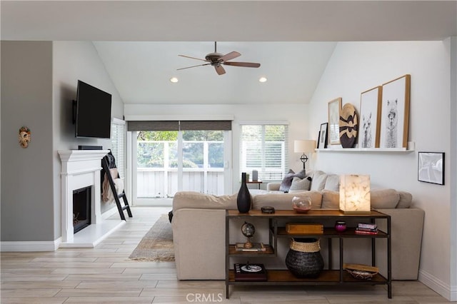 living room with ceiling fan, lofted ceiling, and light wood-type flooring