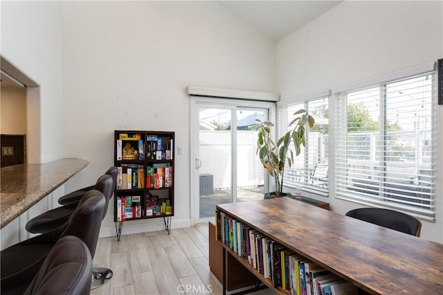 home office featuring high vaulted ceiling and light wood-type flooring