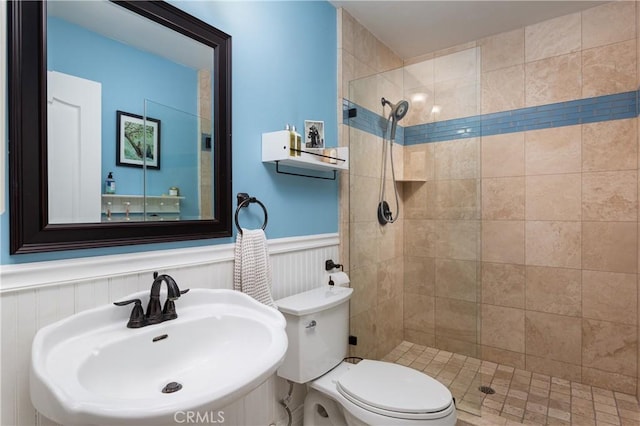 bathroom featuring a tile shower, sink, and toilet