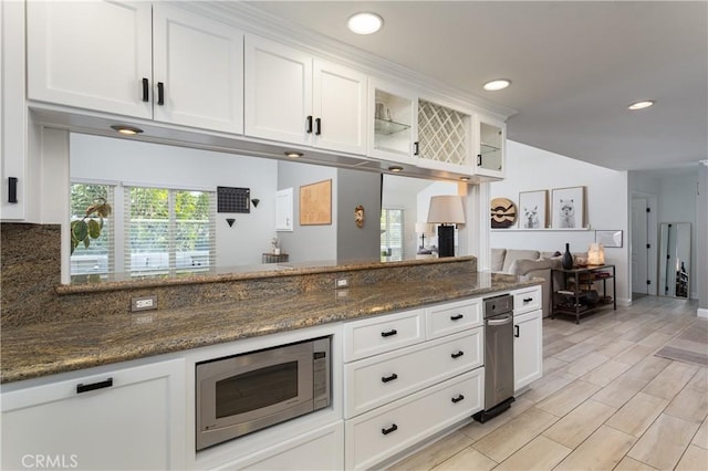 kitchen with white cabinetry, dark stone countertops, and stainless steel microwave