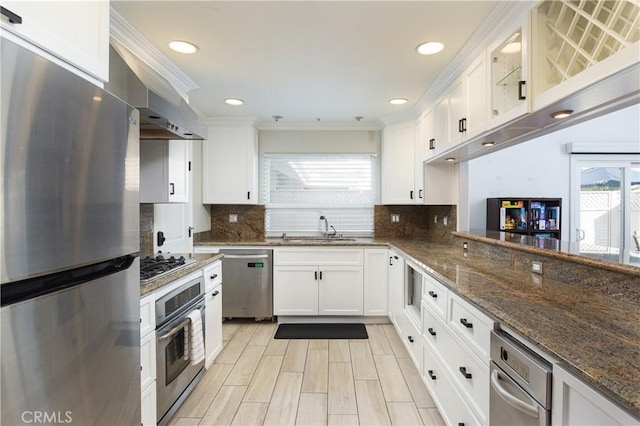 kitchen featuring sink, dark stone countertops, stainless steel appliances, white cabinets, and decorative backsplash