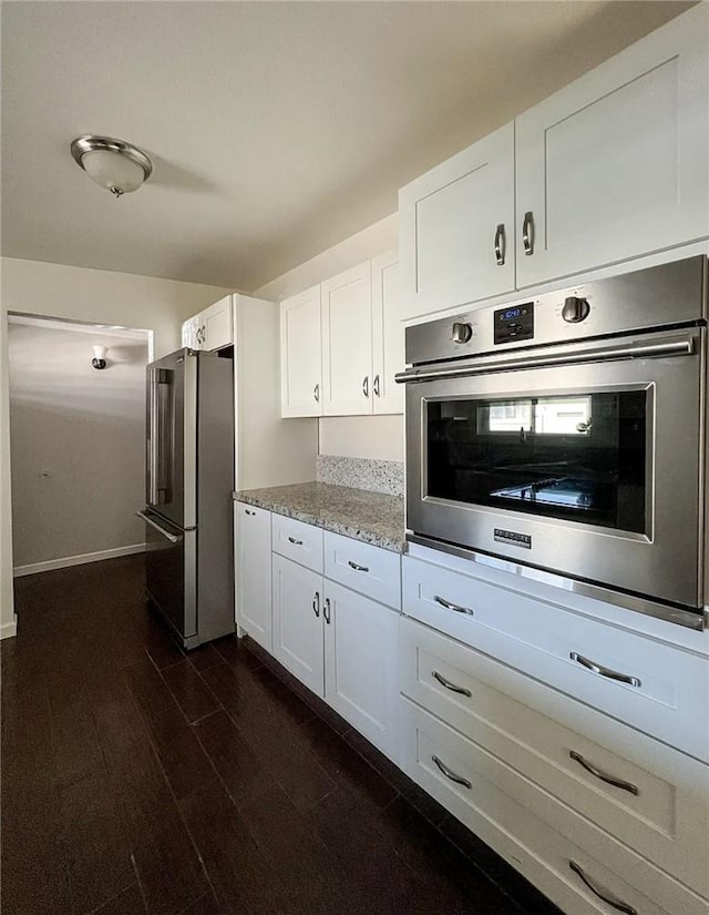 kitchen with white cabinetry, appliances with stainless steel finishes, dark wood-type flooring, and light stone counters