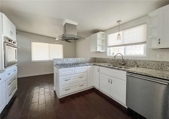 kitchen featuring appliances with stainless steel finishes, island range hood, sink, white cabinets, and light stone countertops