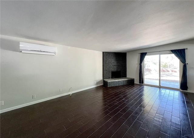 unfurnished living room featuring dark wood-type flooring, a brick fireplace, and an AC wall unit