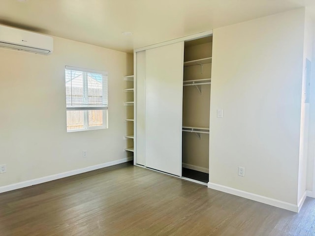 unfurnished bedroom featuring a closet, hardwood / wood-style floors, and a wall unit AC