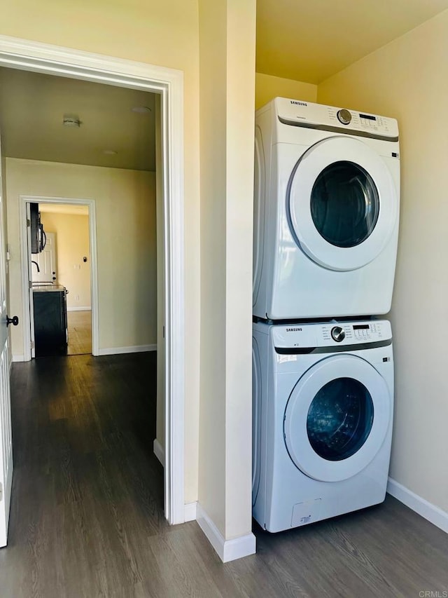 laundry room featuring stacked washer and dryer and dark hardwood / wood-style floors