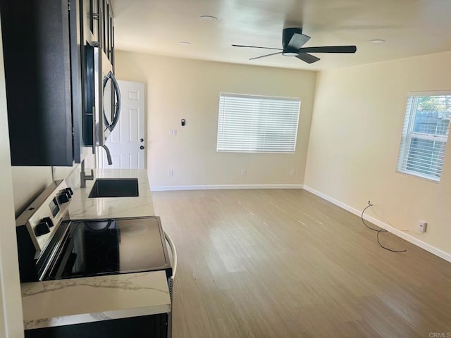 kitchen with sink, light stone counters, light hardwood / wood-style flooring, ceiling fan, and stainless steel appliances