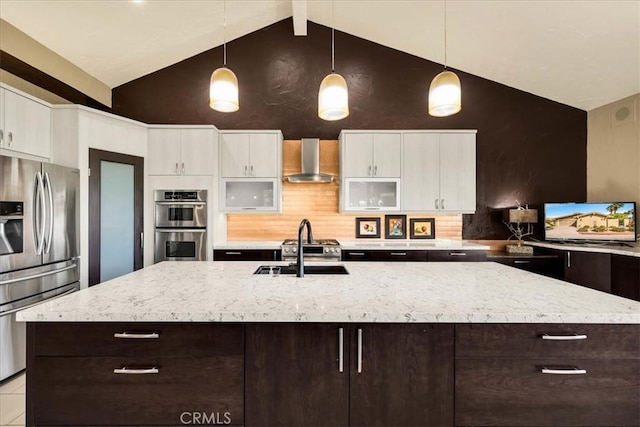 kitchen featuring white cabinets, appliances with stainless steel finishes, decorative light fixtures, and wall chimney range hood