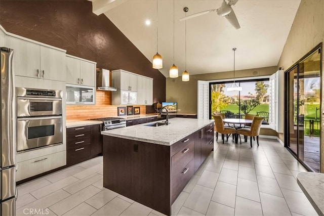 kitchen with a kitchen island with sink, sink, decorative light fixtures, and dark brown cabinetry