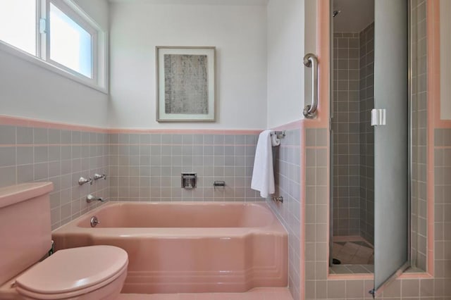 bathroom with independent shower and bath, tile walls, and toilet