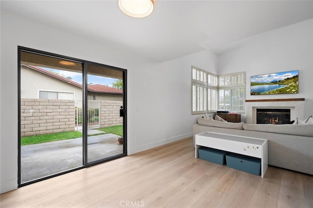 living room featuring plenty of natural light, lofted ceiling, and light wood-type flooring