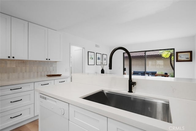 kitchen featuring white cabinetry, sink, white dishwasher, and decorative backsplash