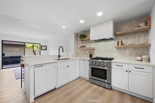 kitchen featuring stainless steel range, white dishwasher, sink, and white cabinets