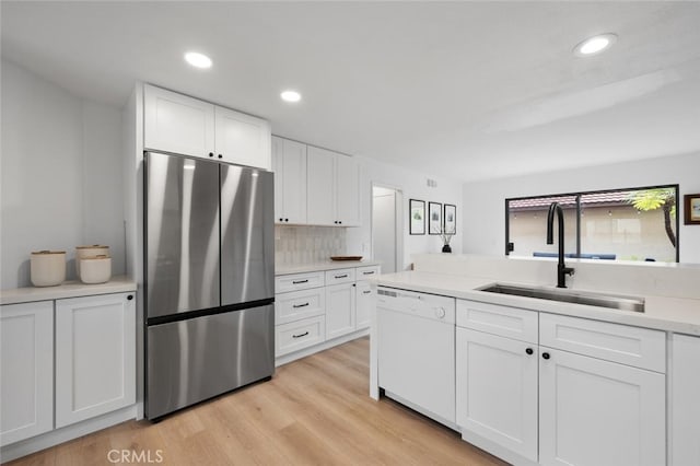 kitchen featuring stainless steel refrigerator, dishwasher, sink, white cabinets, and light hardwood / wood-style flooring