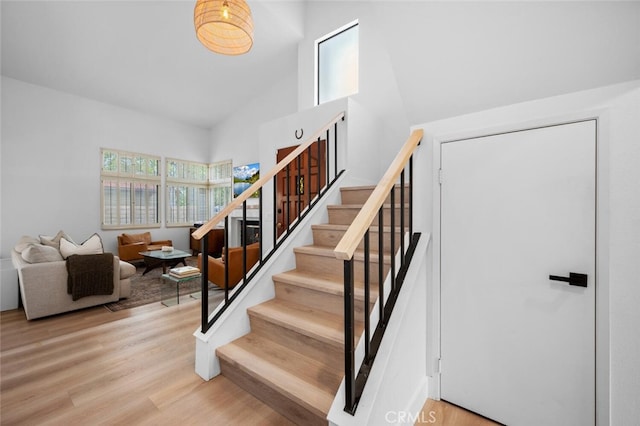 stairs with hardwood / wood-style flooring and high vaulted ceiling