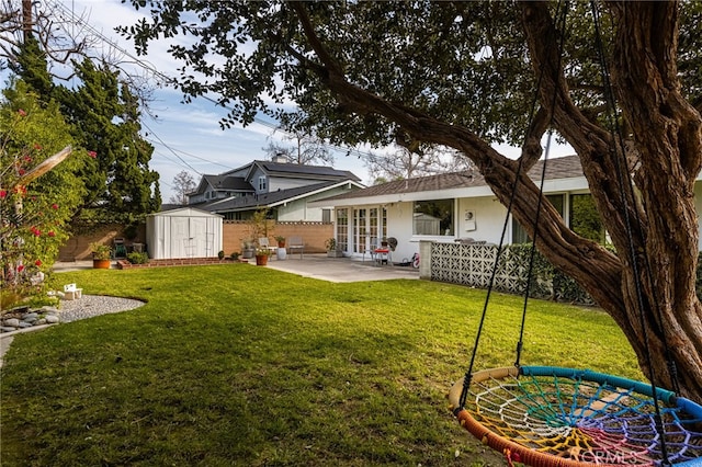 rear view of property featuring an outbuilding, fence, a patio, a storage unit, and a lawn