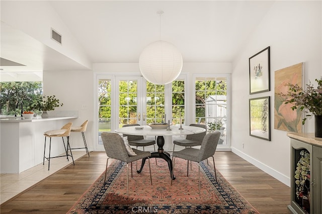 dining space featuring baseboards, lofted ceiling, visible vents, and wood finished floors