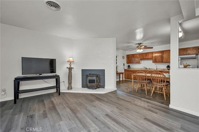 living room with ceiling fan, hardwood / wood-style floors, and a wood stove