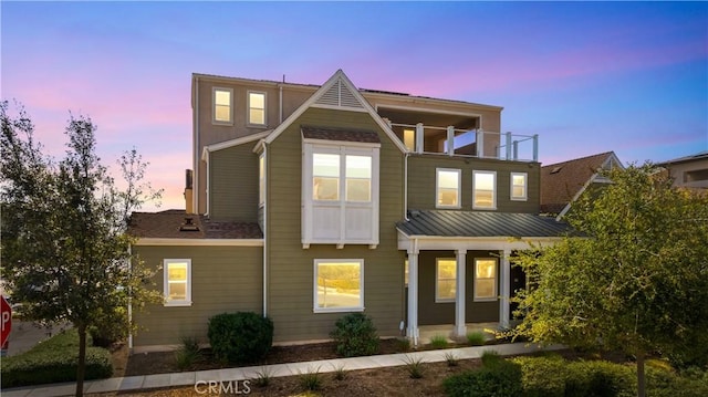 back house at dusk with a balcony