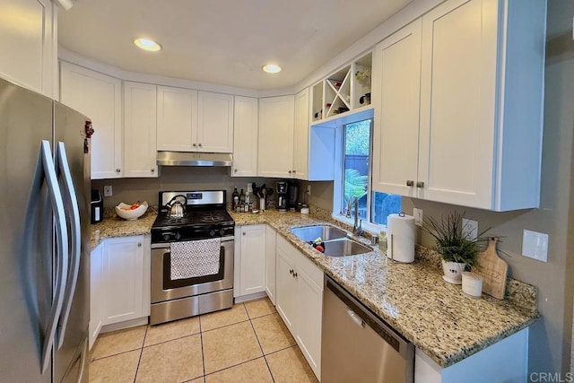 kitchen with light tile patterned flooring, sink, white cabinets, stainless steel appliances, and light stone countertops