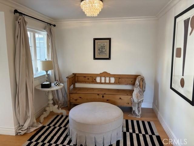 sitting room with a notable chandelier, crown molding, and wood-type flooring