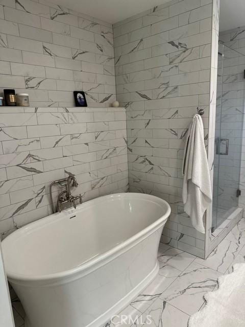 bathroom with tile walls and separate shower and tub