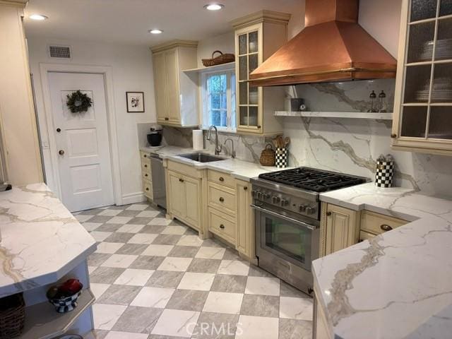 kitchen with premium range hood, stainless steel appliances, and cream cabinetry